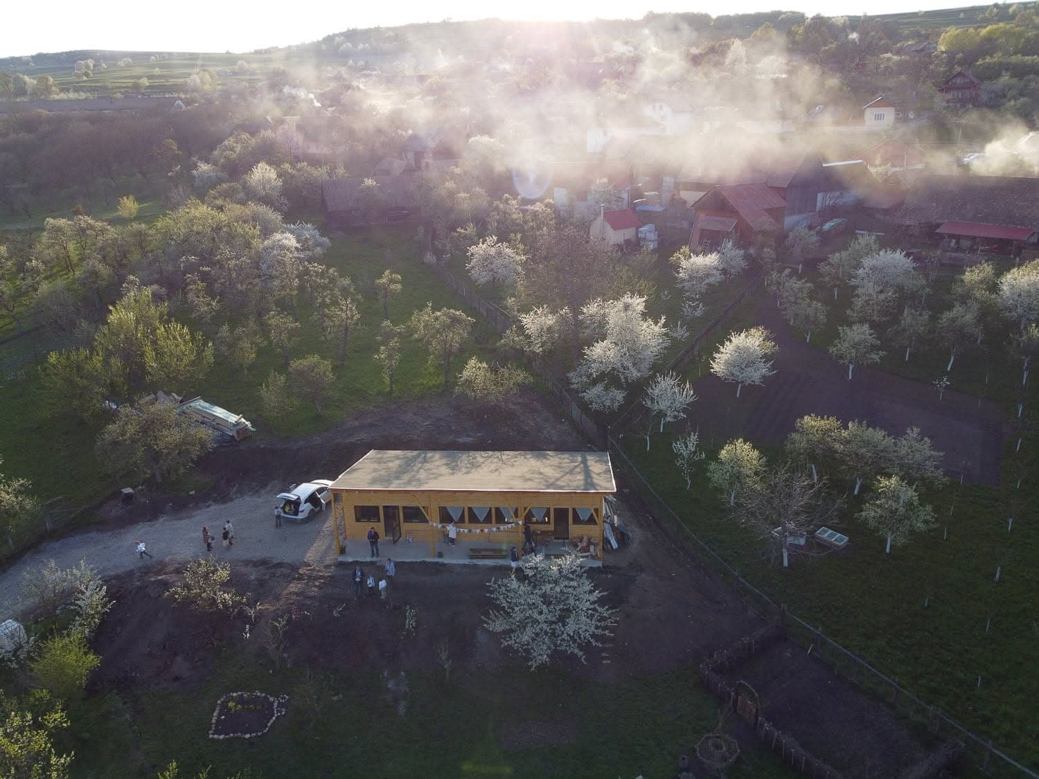 Az új iskolaépület madártávlatból, tavaszi gyümölcsösök között